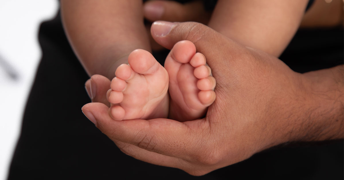 Person holding newborn baby feet. Credit / Shutterstock