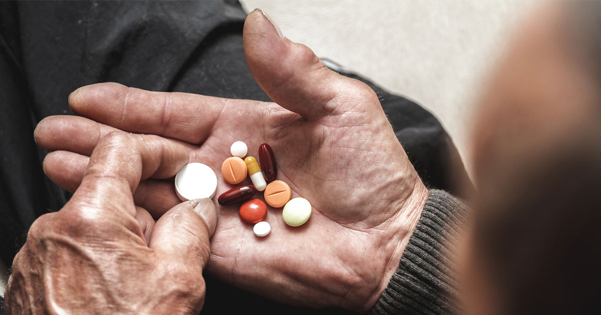 Older man's hand holding pills. Credit / Shutterstock