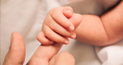 Baby holds finger. (Stock image). Credit / Shutterstock