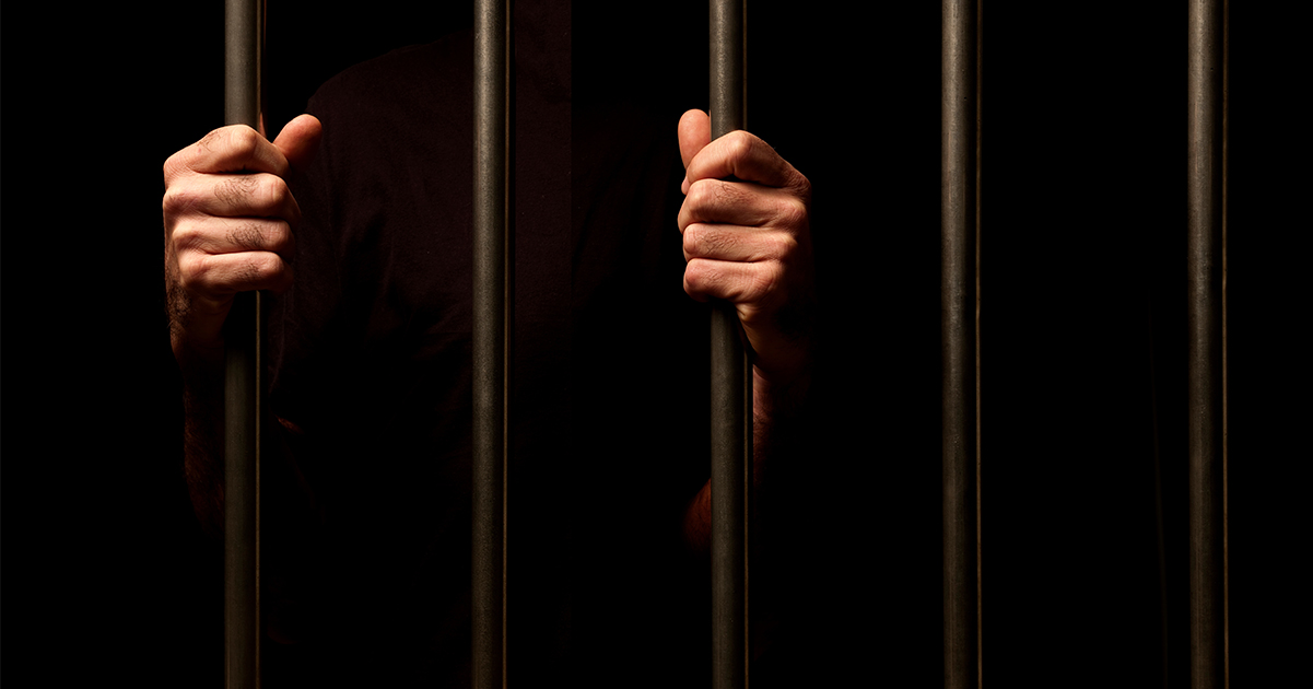 Hands grip prison bars. (Stock Image) Credit / Shutterstock