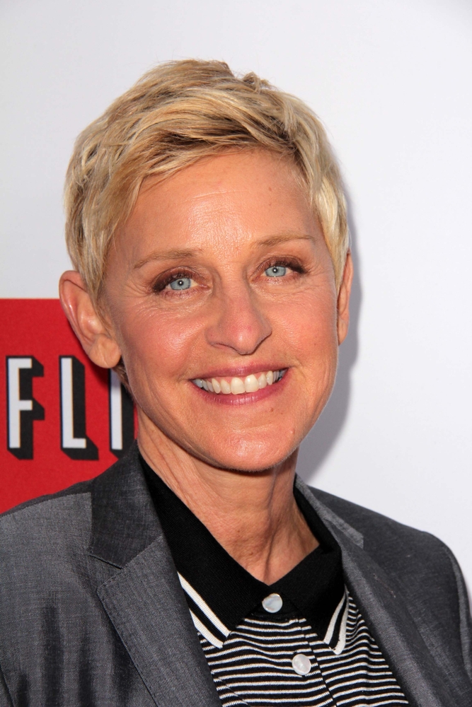 Ellen DeGeneres w szarej marynarce i bluzce z kołnierzykiem 