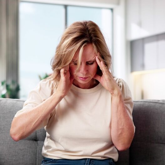 kobieta pochyla głowę i trzyma się za nią rękoma