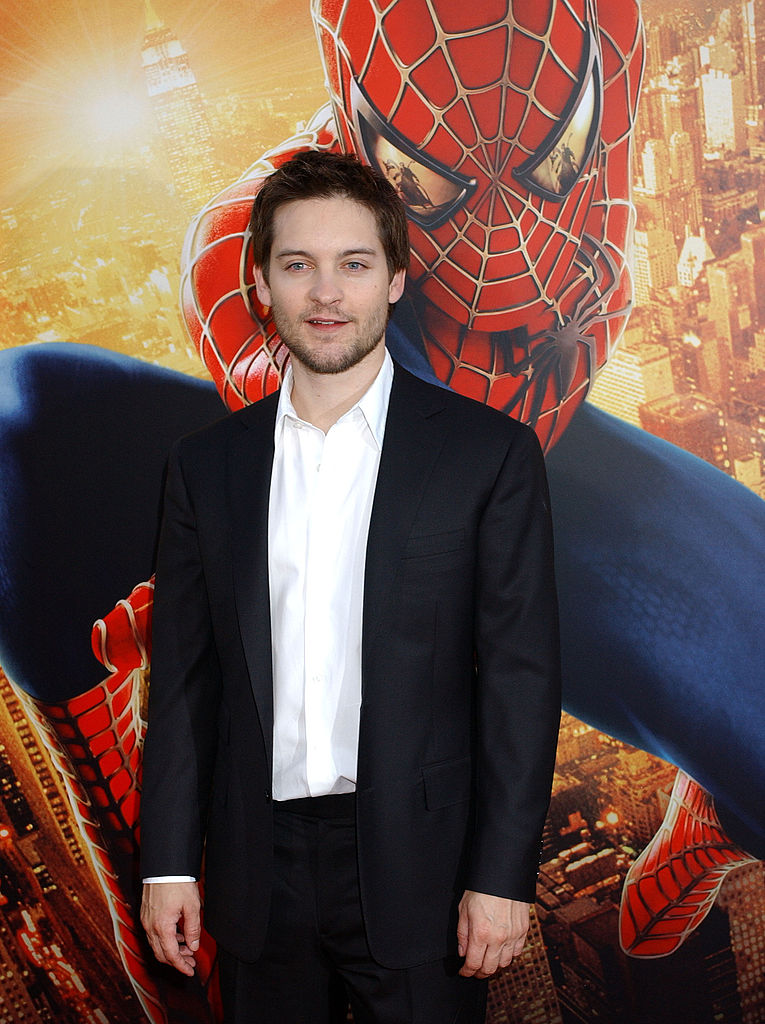 Tobey Maguire w garniturze na tle plakatu z postacią Spidermana
