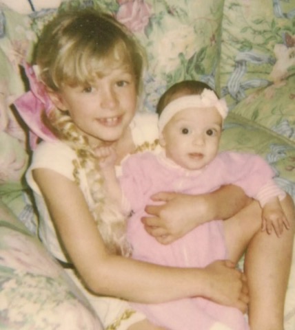 blondwłosa dziewczynka trzyma na rękach niemowlę