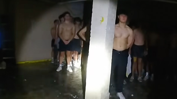 młodzi mężczyźni stoją w ciemnościach bez koszulek