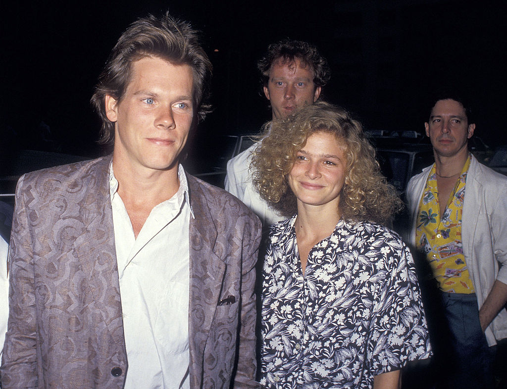 uśmiechnięci Kevin Bacon i Kyra Sedgwick, a za nimi dwaj mężczyźni