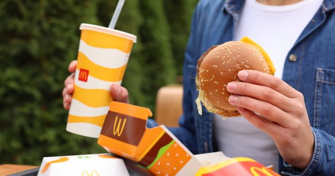 ktoś trzyma w ręku burgera i napój z McDonald’s