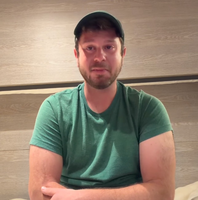 Jake Rosmarin, influencer podróżniczy w czapeczce z daszkiem  i zielonej koszulce