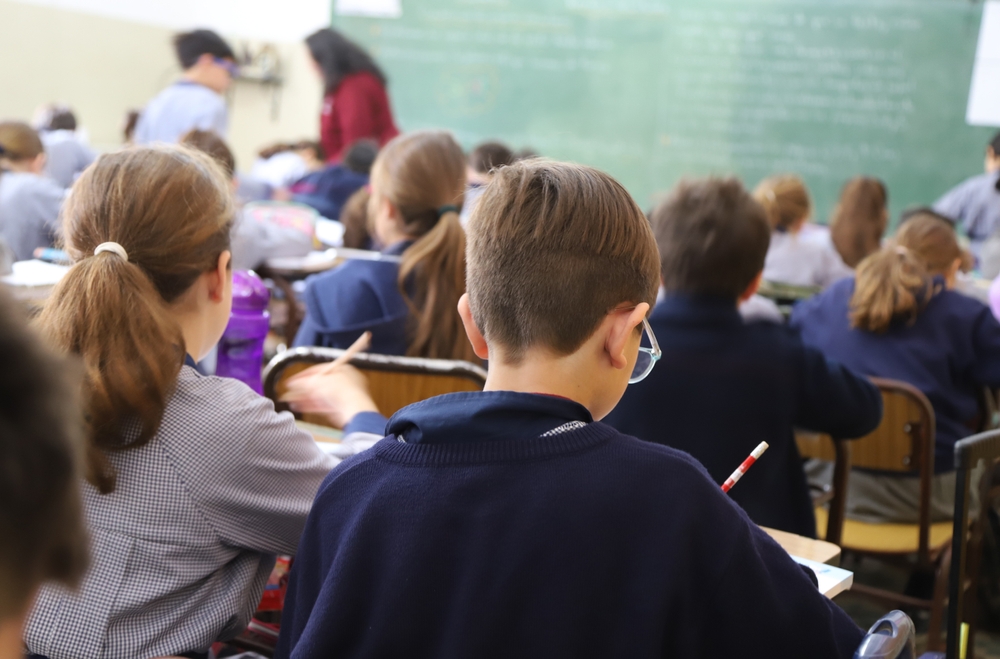 dzieci siedzą w ławkach w sali lekcyjnej