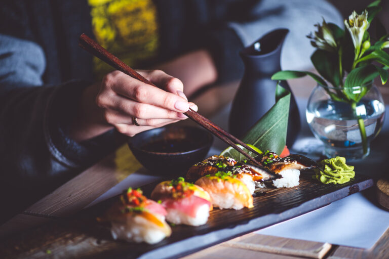 człowiek je sushi przy użyciu pałeczek