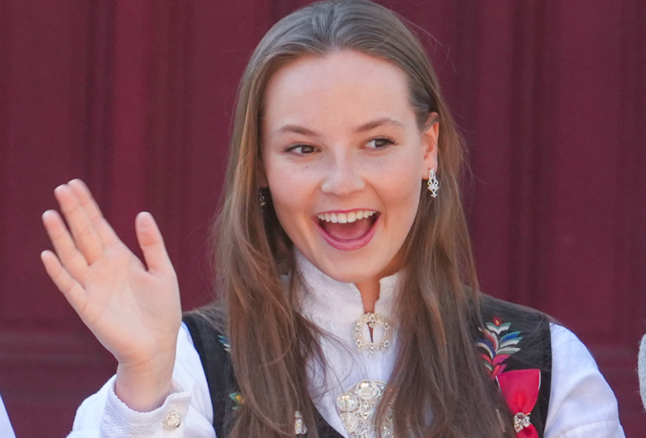 Kronprinsesse Mette-Marit, kronprins Haakon og prinsesse Ingrid Alexandra hilser i barnetoget under 17.mai-feiringen på Skaugum.
