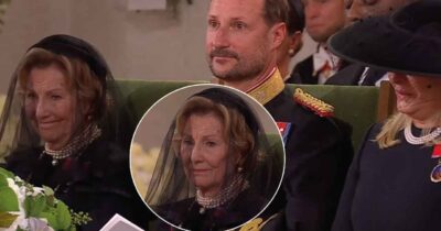 Dronning Sonja i sørgebind sitter ved siden av kronprins Haakon ved en begravelsesseremoni