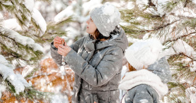 Mor og datter dekorerer et træ i snevejr