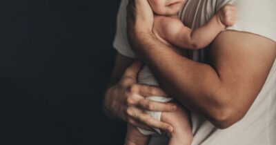 Padre tiene figlio in braccio.