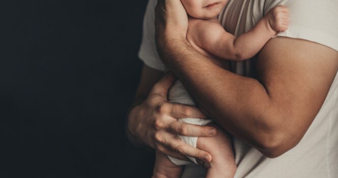 Padre tiene figlio in braccio.