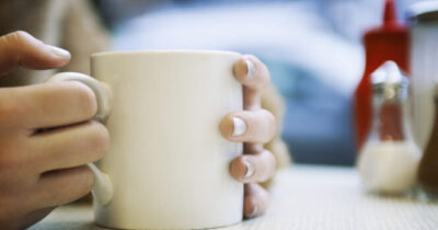 Mani stringono una tazza.