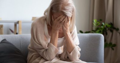 Una donna si copre il viso con le mani.