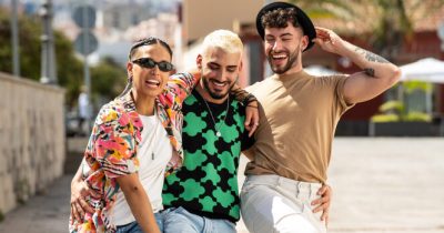 Tre persone si abracciano sorridenti.