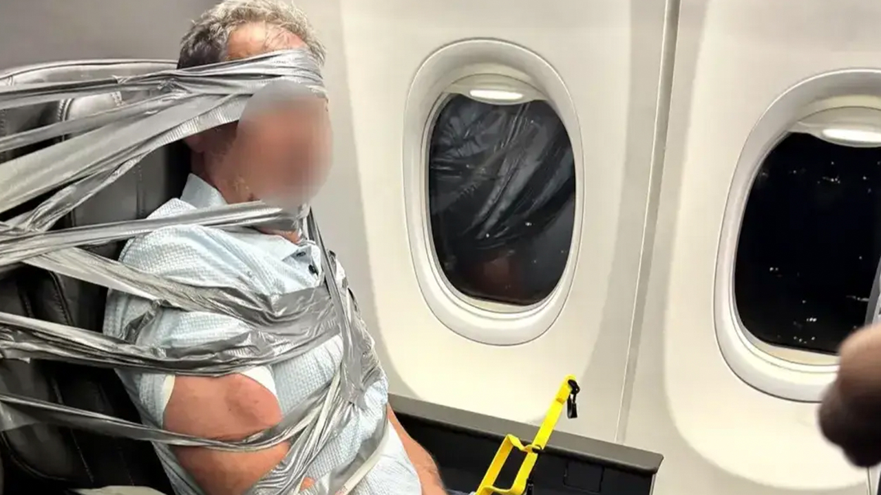 Paseggero legato al sedile con nastro adesivo su un aereo.