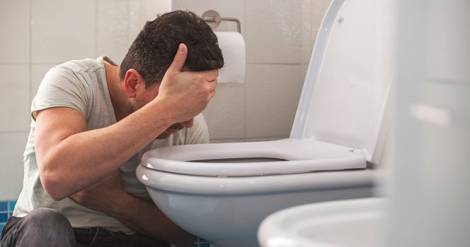un homme vomit dans les toilettes