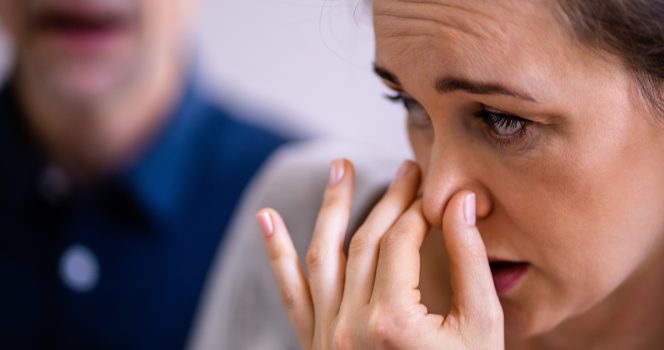 Une femme qui se tient le nez